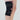 Black knee brace on a person's leg with a plain background